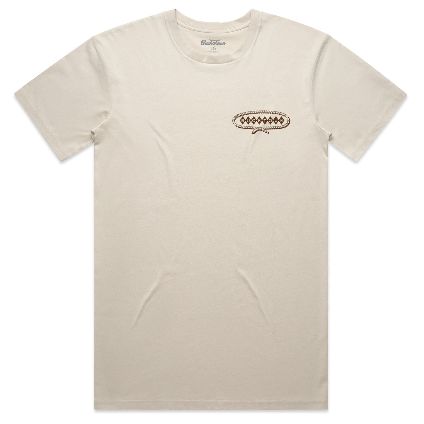 The Bucktown Caddie Tee by Rural Cloth is a plain beige short-sleeve shirt with a small brown and black oval geometric design on the left chest. The collar tag shows the size and brand name.