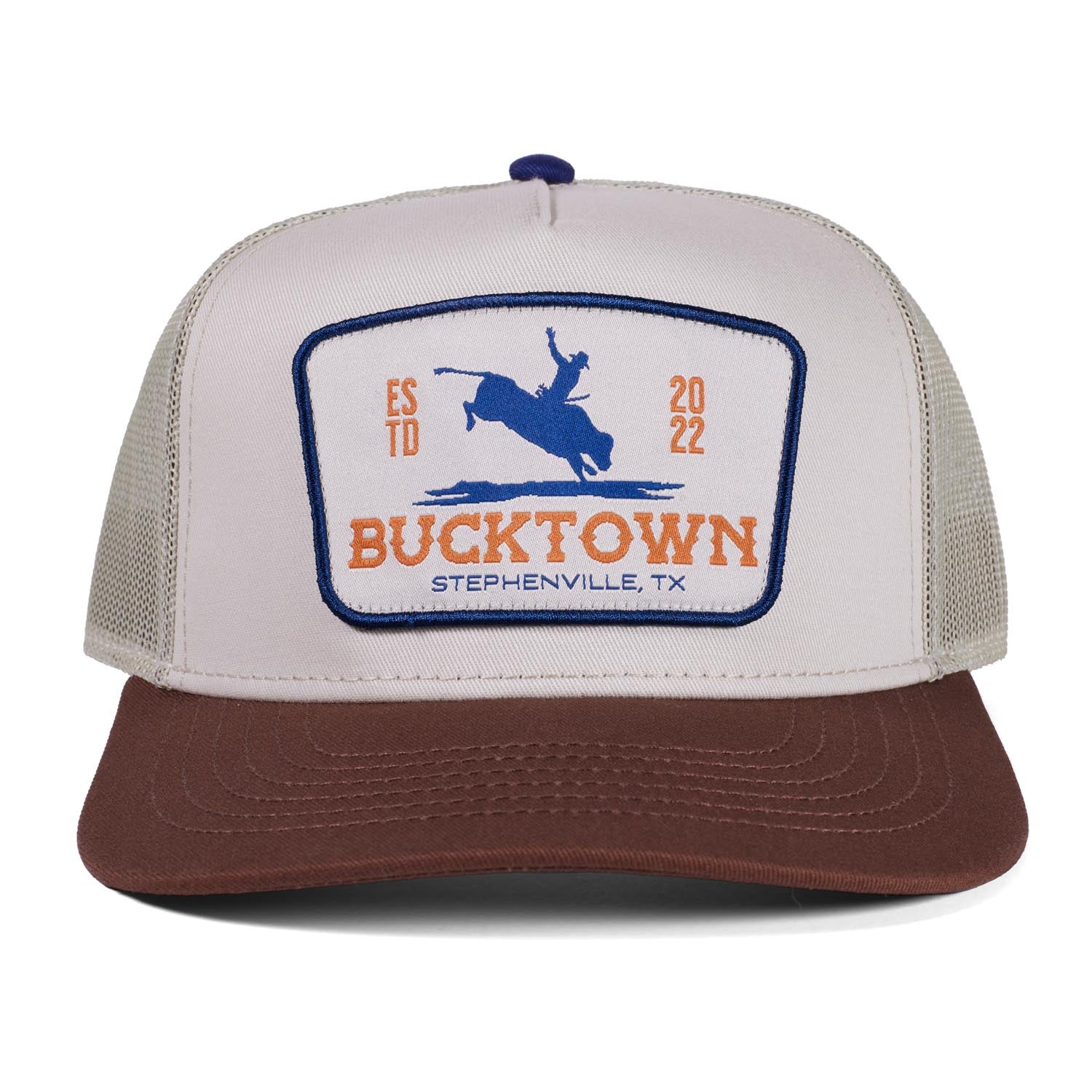 The Rural Cloth Last Out Hat is a two-tone western snapback with a white front, brown bill, and a patch reading "Bucktown Stephenville, TX" plus a bucking horse, "ESTD 2022," and Bucktown XV Ranch in orange and blue.