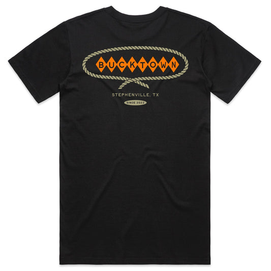 Show your Western pride in the black Stephenville Tee by Rural Cloth, featuring a western-style Bucktown diamond logo, orange "BUCKTOWN" diamonds, rope border, and "STEPHENVILLE, TX" with "Since 2002" below.