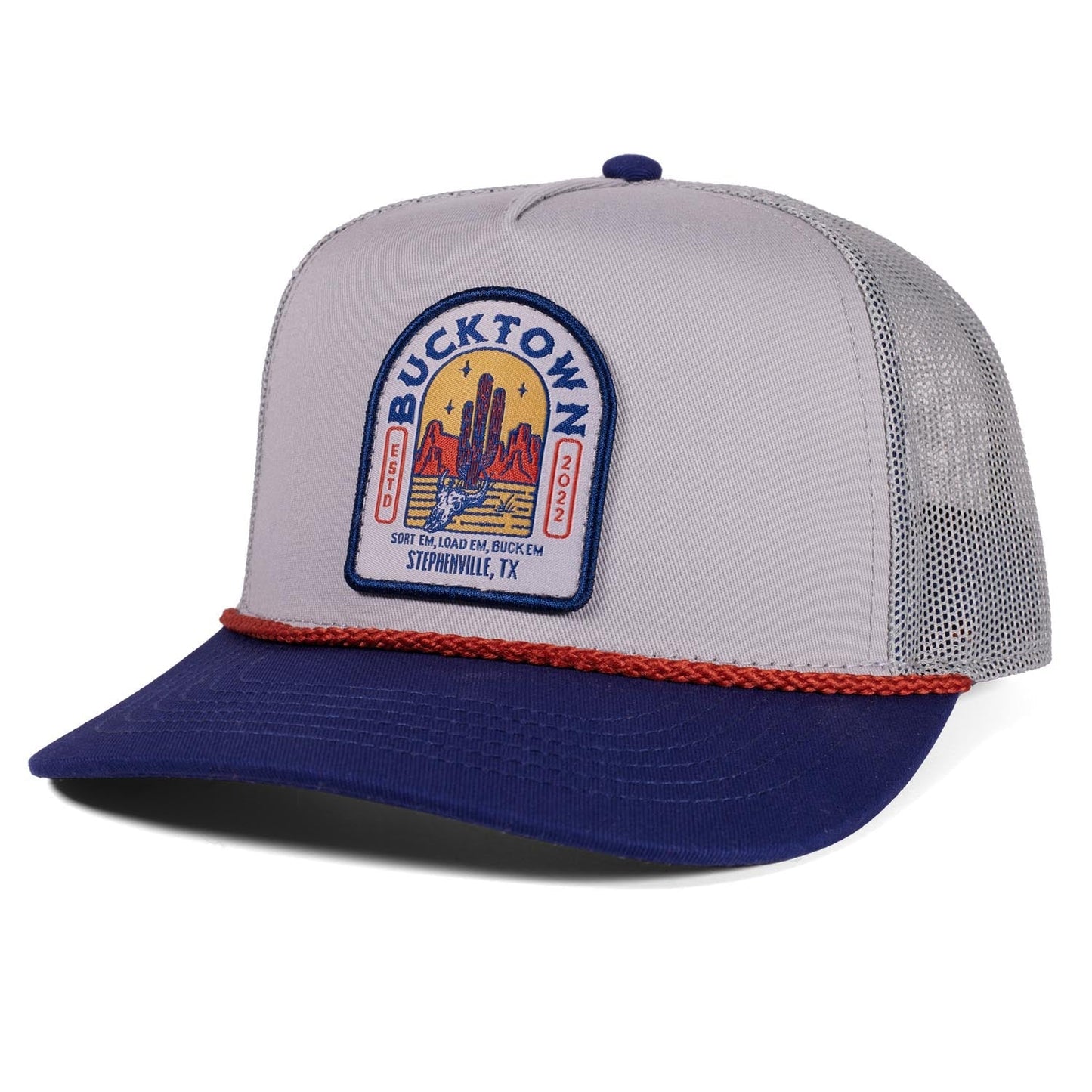 The Sundown Hat by Rural Cloth is a gray and blue western snapback trucker with mesh back, red rope above the brim, and a front patch showing cacti and "BUCKTOWN XV Ranch.